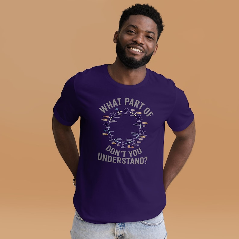 May include: A dark purple t-shirt with the text "WHAT PART OF DON'T YOU UNDERSTAND?" in white. The shirt features a circular diagram with scientific symbols. The person wearing the shirt is smiling.