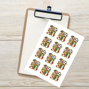 May include: A sheet of stickers featuring a soccer ball, the number 20, and flags of the United States and Mexico. The stickers are on a white sheet, resting on a wooden clipboard.