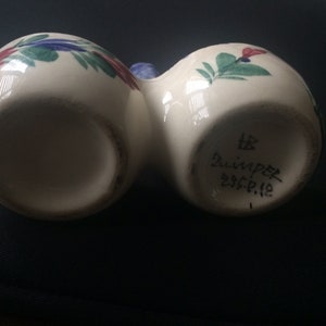 May include: White ceramic salt and pepper shakers with blue and green floral designs. The bottom of the shakers are marked with "HB Zwinger 235.P.12".