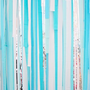 May include: A backdrop of blue and white streamers hanging from the ceiling. The streamers are made of tissue paper and are arranged in a random pattern.