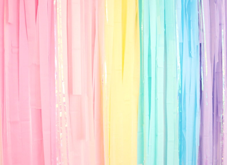 May include: A rainbow-colored streamer backdrop with vertical strips of pink, yellow, light blue, and purple.
