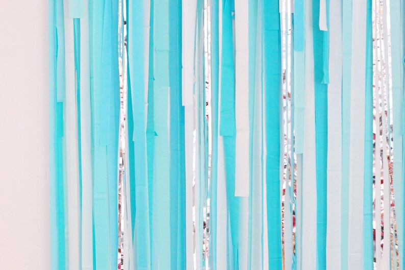 May include: A wall decorated with a curtain of blue and white streamers. The streamers are hanging from the ceiling and are arranged in a random pattern.