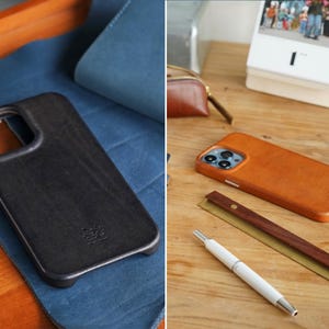 May include: Two leather phone cases, one black and one brown, displayed on a wooden surface. The black case rests on blue fabric. A white pen and a wooden ruler are next to the brown case. A calendar is in the background.