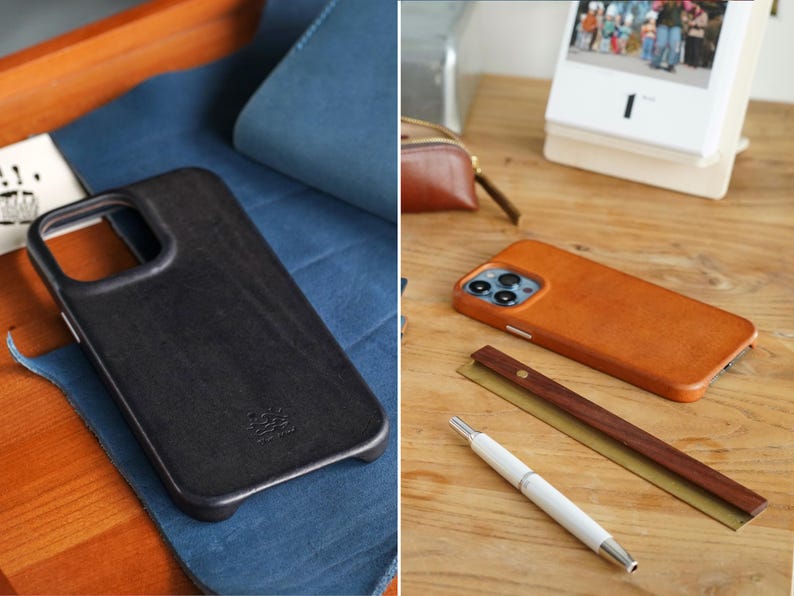 May include: Two leather phone cases, one black and one brown, displayed on a wooden surface. The black case rests on blue fabric. A white pen and a wooden ruler are next to the brown case. A calendar is in the background.
