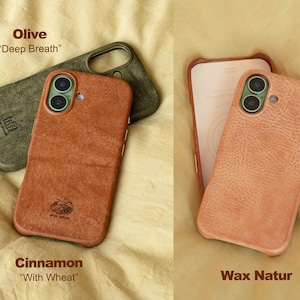 May include: An overhead shot displays three phone cases in various colors. The top case is olive green, the middle case is cinnamon, and the right case is a light peach color. The cinnamon case has the text "With Wheat" and the olive case has the text "Deep Breath".