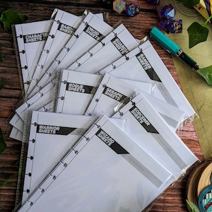 Könnte beinhalten: Eine Sammlung weißer Charakterbögen für Tabletop-Rollenspiele. Jedes Blatt ist mit einem Klassennamen wie "Warrior Sheets", "Wizard Sheets" und "Rogue Sheets" beschriftet. Die Blätter sind in klarem Kunststoff verpackt.