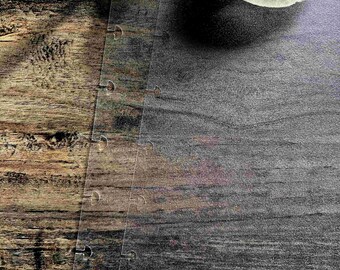 Puede incluir: Primer plano de una superficie de veta de madera con un trozo de plástico transparente con una serie de agujeros a lo largo del borde. El plástico cubre parcialmente una superficie gris oscuro.