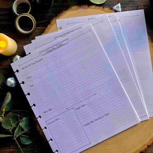 May include: A stack of lined, light purple planner pages with the text "Story Arc Outline" and other prompts for game planning. The pages are hole-punched for a binder. Other items in the image include dice, washi tape, and a candle.