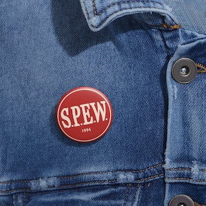 May include: Red button with white text that reads "S.P.E.W." and "1994".
