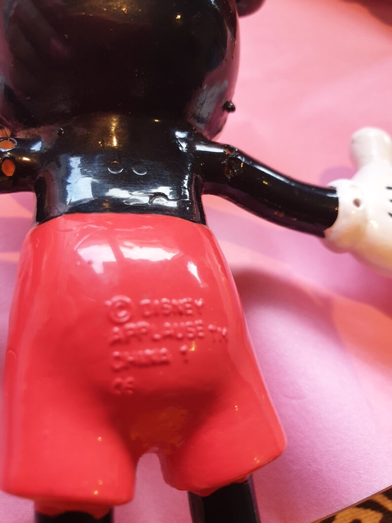 Peut inclure: Figurine vintage de Mickey Mouse, avec un corps noir brillant, un short rouge et des gants blancs. La figurine porte du texte au dos, dont les marques Disney et Applause. La figurine est pos&eacute;e avec les bras tendus.