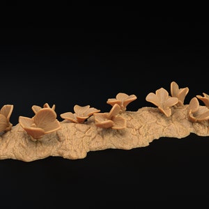 May include: A miniature terrain piece featuring a cluster of brown, flower-like structures growing from a textured, tan-colored base.