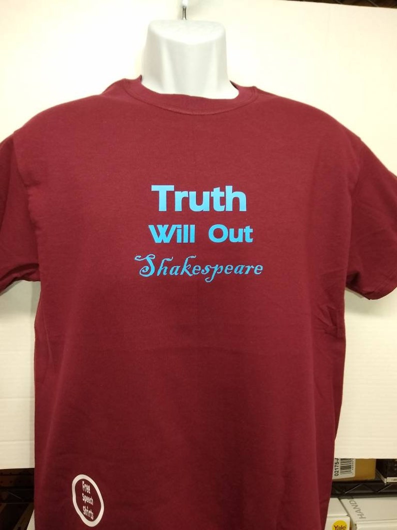 May include: A maroon t-shirt with the text "Truth Will Out Shakespeare" in blue lettering.