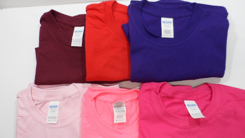 May include: Six folded Gildan brand t-shirts in various colors: maroon, red, purple, pink, light pink, and hot pink.