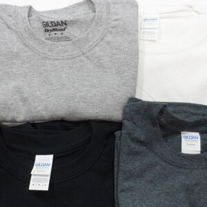 May include: Four folded Gildan brand t-shirts in different colors: gray, black, dark gray, and white.