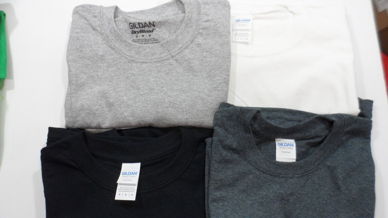 May include: Four folded Gildan brand t-shirts in different colors: gray, black, dark gray, and white.