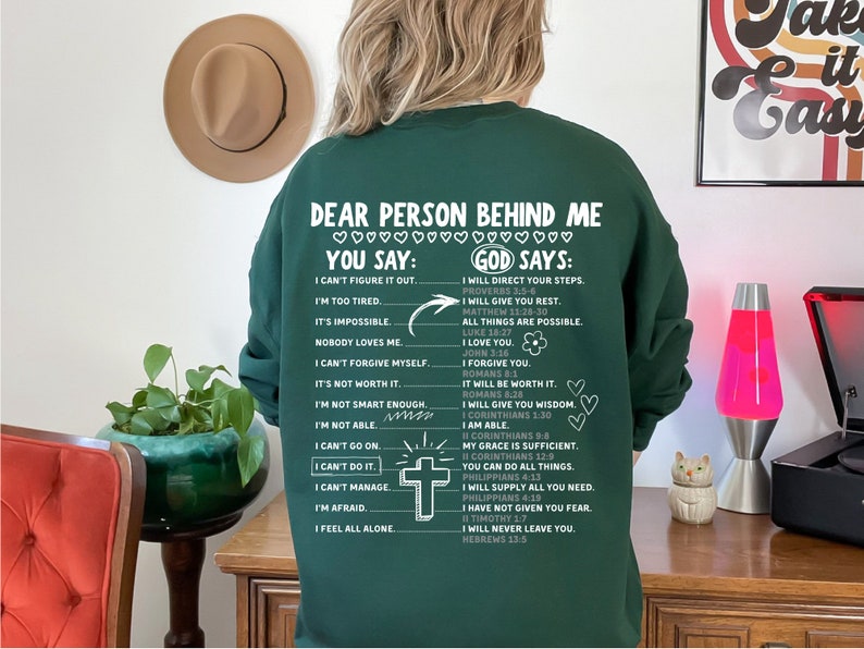 May include: Green sweatshirt with a white print that says "Dear person behind me" and lists encouraging phrases with the words "You say" and "God says".