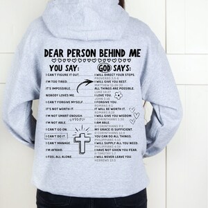 May include: Gray hooded sweatshirt with a motivational message printed on the back. The text reads "Dear person behind me... You say: I can't figure it out... God says: I will direct your steps..." and includes several Bible verses.