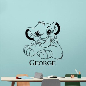 May include: Black and white line art wall decal of a cartoon lion cub with the name "GEORGE" underneath.