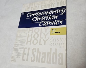 May include: A sheet music book titled "Contemporary Christian Classics" for piano. The cover is white with a blue banner and text in white and yellow. The text includes "HOLY", "Easter Song", and "El Shaddai".