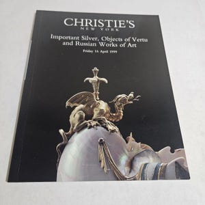 May include: A catalog from Christie's New York, featuring the title "Important Silver, Objects of Vertu and Russian Works of Art." The cover displays a gold sculpture of a dragon atop a pearl-like object, with the date "Friday 16 April 1999."