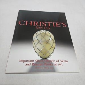 May include: A book cover with the text "CHRISTIE'S New York" in red. Below is a silver-wired egg-shaped object. The text "Important Silver, Objects of Vertu and Russian Works of Art" is below the egg. The date "FRIDAY 11 APRIL 2003" is at the bottom.