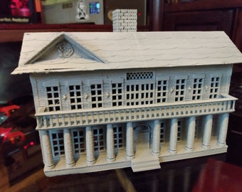 May include: A gray 3D printed model of a two-story house with a white roof, a chimney, and a balcony. The house has multiple windows and a front door.