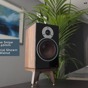 May include: A walnut wood speaker with a black front and a 140mm woofer. The speaker is on a wooden stand with three legs. The text "The Snipe 140mm Material Shown: Walnut" is visible in the image.
