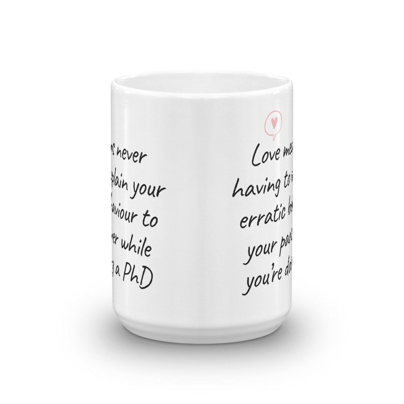 Puede incluir: Taza de caf&eacute; de cer&aacute;mica blanca con texto negro que dice "never explain your behaviour to someone while getting a PhD" en el lado izquierdo y "Love means having to explain your erratic behaviour to your partner when you're drunk" en el lado derecho. Hay un peque&ntilde;o coraz&oacute;n rosa en un globo de di&aacute;logo sobre el texto en el lado derecho.