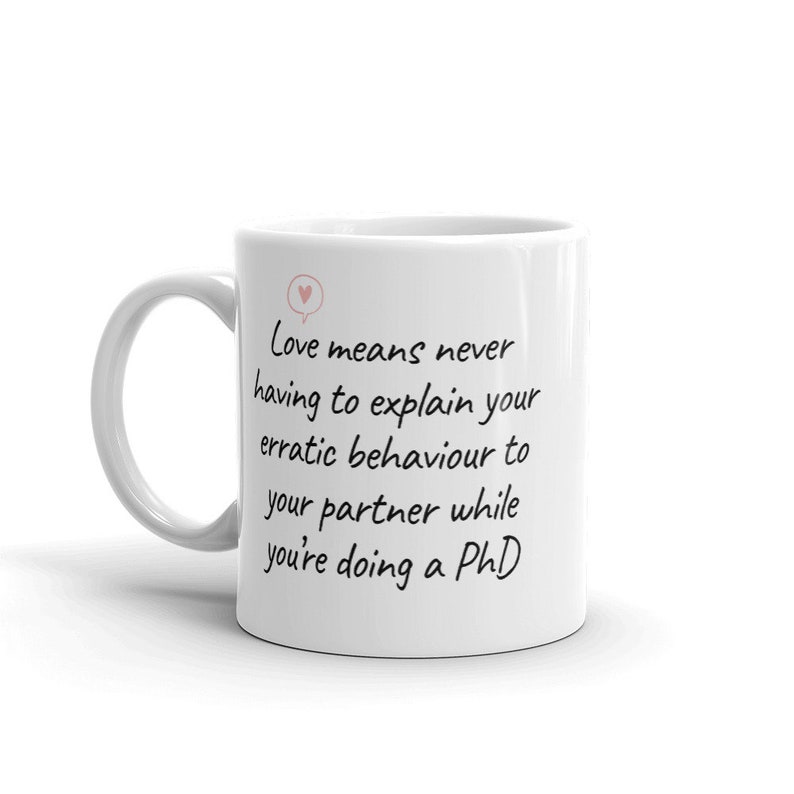 Puede incluir: Taza de cer&aacute;mica blanca con un mensaje escrito a mano en negro que dice "El amor significa no tener que explicar nunca tu comportamiento err&aacute;tico a tu pareja mientras haces un doctorado".