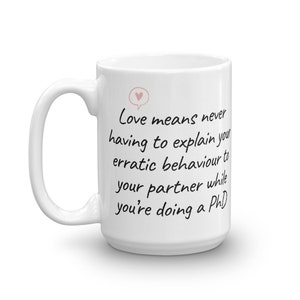 Puede incluir: Taza de cer&aacute;mica blanca con una cita manuscrita en negro que dice "El amor significa no tener que explicar nunca tu comportamiento err&aacute;tico a tu pareja mientras haces un doctorado".