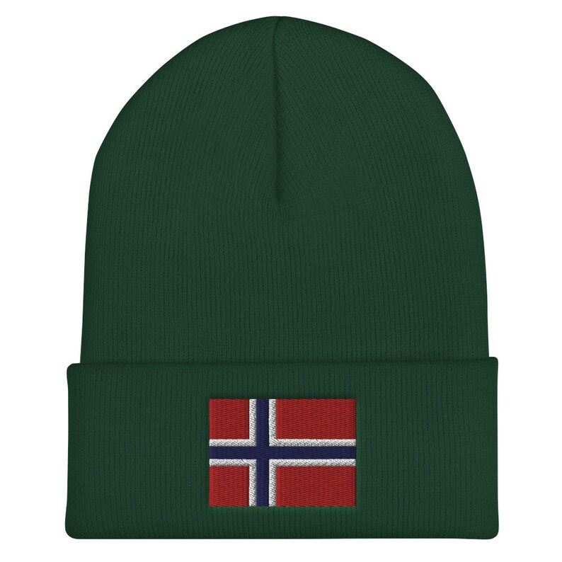 May include: A dark green beanie with a folded brim. The beanie features an embroidered Norwegian flag patch on the front. The flag has a red background with a white-bordered blue cross.