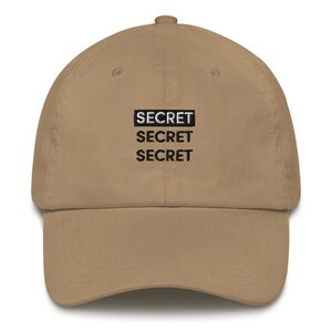 May include: A tan baseball cap with the word "SECRET" repeated three times in black text.