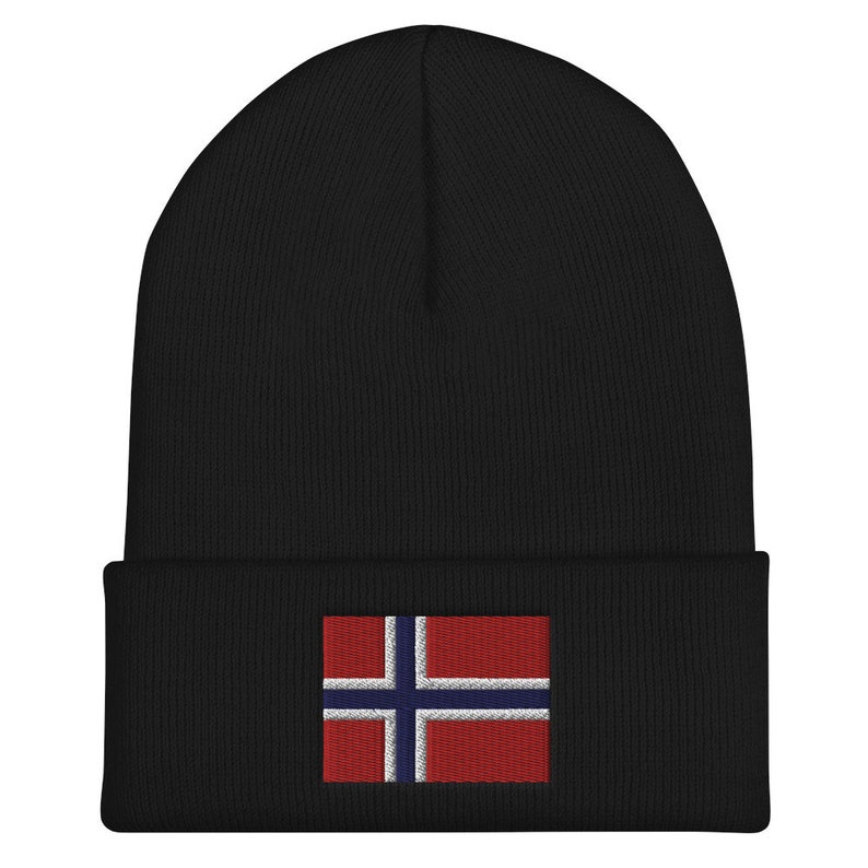 May include: Black beanie with a folded brim. The beanie features an embroidered Norwegian flag patch on the front. The flag design includes a blue cross with white borders on a red background. The beanie is made of a soft, knitted material.