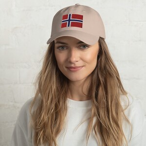 K&ouml;nnte beinhalten: Eine beige Baseballkappe mit einer gestickten norwegischen Flagge auf der Vorderseite.