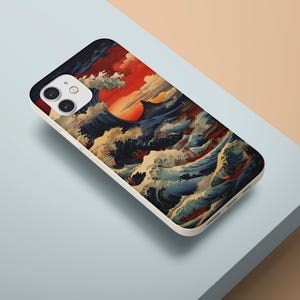 May include: A phone case featuring a Japanese-style wave design with a setting sun. The case has a white border and a colorful illustration of ocean waves in shades of blue, white, and red.