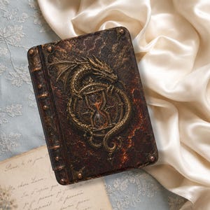 May include: A rectangular book cover featuring a dark brown and black textured surface with a raised, metallic gold-toned dragon coiled around a central hourglass emblem. The spine area includes decorative metal studs at the top and bottom corners.