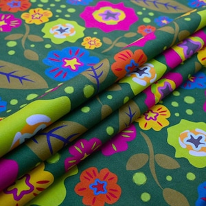 May include: A folded fabric with a floral pattern. The design features large, colorful flowers in shades of pink, orange, yellow, and blue against a dark green background. The fabric also has leaves and small dots.