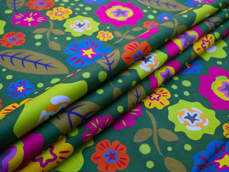 May include: A folded fabric with a floral pattern. The design features large, colorful flowers in shades of pink, orange, yellow, and blue against a dark green background. The fabric also has leaves and small dots.
