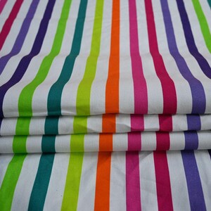 May include: Folded fabric with vertical stripes in a rainbow of colors: purple, green, orange, pink, and white. The stripes are evenly spaced and run the length of the fabric. The fabric is folded over on itself.