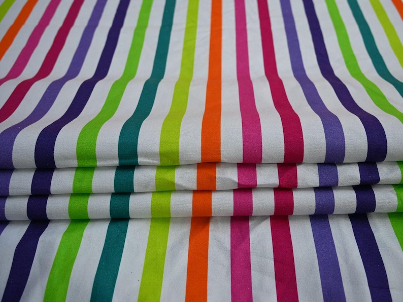 May include: Folded fabric with vertical stripes in a rainbow of colors: purple, green, orange, pink, and white. The stripes are evenly spaced and run the length of the fabric. The fabric is folded over on itself.
