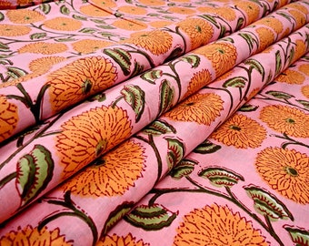 May include: Pink fabric with a repeating pattern of orange flowers. The fabric is folded in thirds, showing the pattern from different angles.