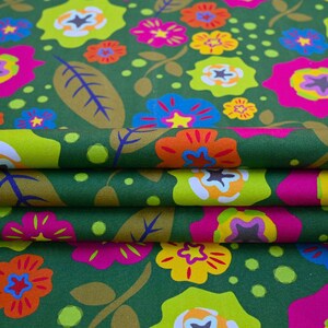 May include: Close-up of folded fabric with a repeating floral pattern. The design features large, colorful flowers in shades of pink, yellow, orange, and blue against a dark green background. The fabric also has green leaves and small green dots.