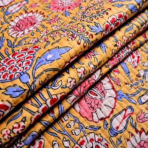 Può includere: Un tessuto giallo con una stampa floreale in tonalità di rosa, blu e rosso. Il tessuto è trapuntato e ha una superficie testurizzata.