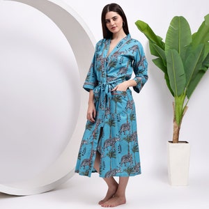 May include: A light blue robe with a long-sleeved design and a tie belt. The robe features a print of elephants and palm trees.