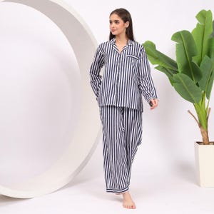 Pu&ograve; includere: Un pigiama a righe bianche e blu navy con una parte superiore con colletto e pantaloni lunghi.