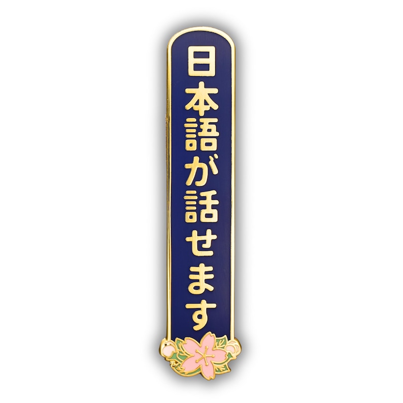Peut inclure: &Eacute;pinglette bleu marine et dor&eacute;e avec le texte japonais "日本語が話せます" en lettres dor&eacute;es. L'&eacute;pinglette a une bordure dor&eacute;e et un motif floral au bas avec des fleurs roses et blanches.