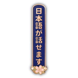 Peut inclure: &Eacute;pinglette rectangulaire avec un fond bleu et une bordure dor&eacute;e. L'&eacute;pinglette pr&eacute;sente des caract&egrave;res japonais dor&eacute;s et une fleur rose et blanche en bas. Le texte sur l'&eacute;pinglette se traduit par "Je parle japonais."