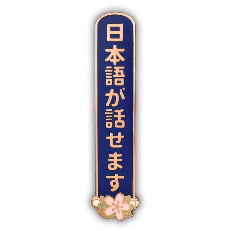 Peut inclure: &Eacute;pinglette rectangulaire avec un fond bleu et une bordure dor&eacute;e. L'&eacute;pinglette pr&eacute;sente des caract&egrave;res japonais dor&eacute;s et une fleur rose et blanche en bas. Le texte sur l'&eacute;pinglette se traduit par "Je parle japonais."