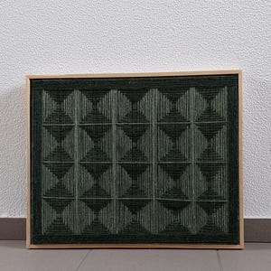 Può includere: Un'opera d'arte geometrica incorniciata in verde e nero con una trama tessuta. L'opera d'arte è in una cornice di legno.