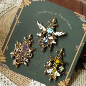 May include: Three gold-toned enamel pins featuring intricate designs. The pins depict a winged hourglass, a scale with a sword, and a scale with a lantern. The pins are set against a green background with gold accents.